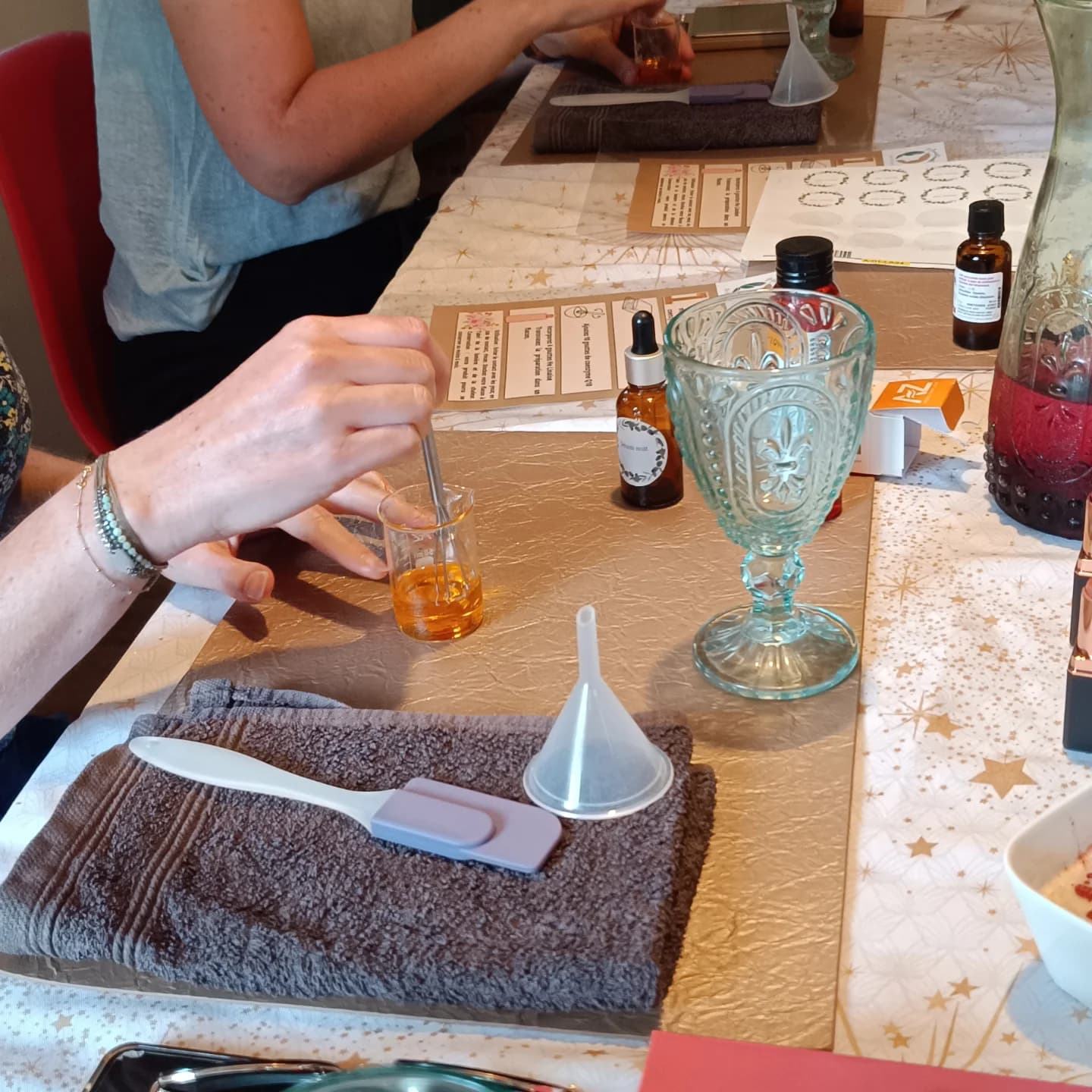 Des participantes mélangent une préparation cosmétique dans des béchers pendant un atelier de Monia.