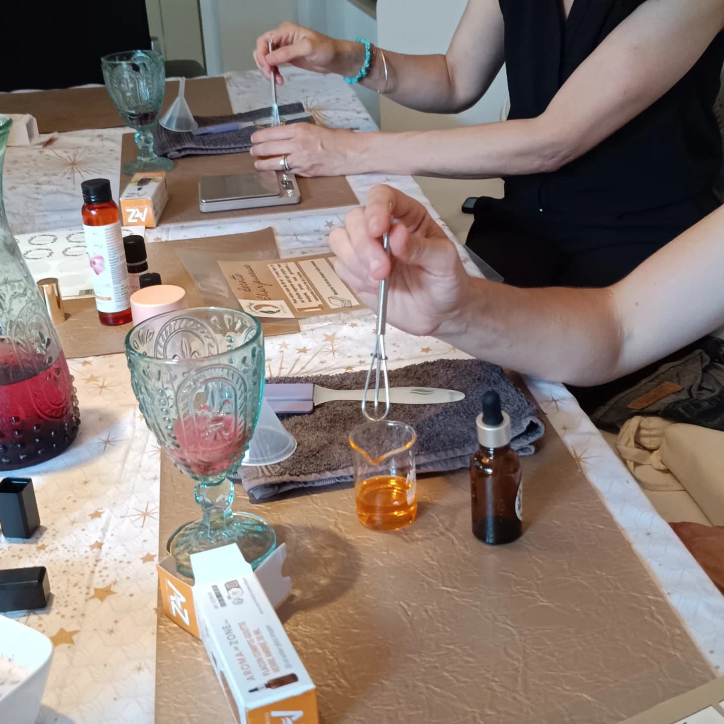 Préparations cosmétiques, petits fouets, flacons et balances sur la table d’un atelier pratique de Monia.